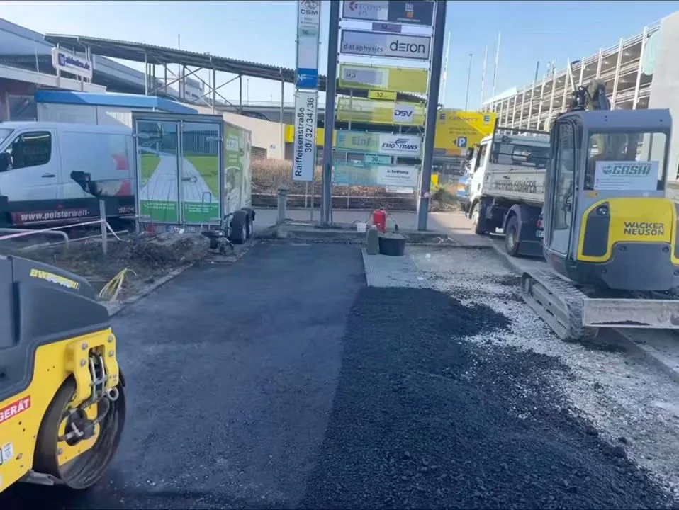 Asphaltierung einer Fläche mit Walze und Bagger