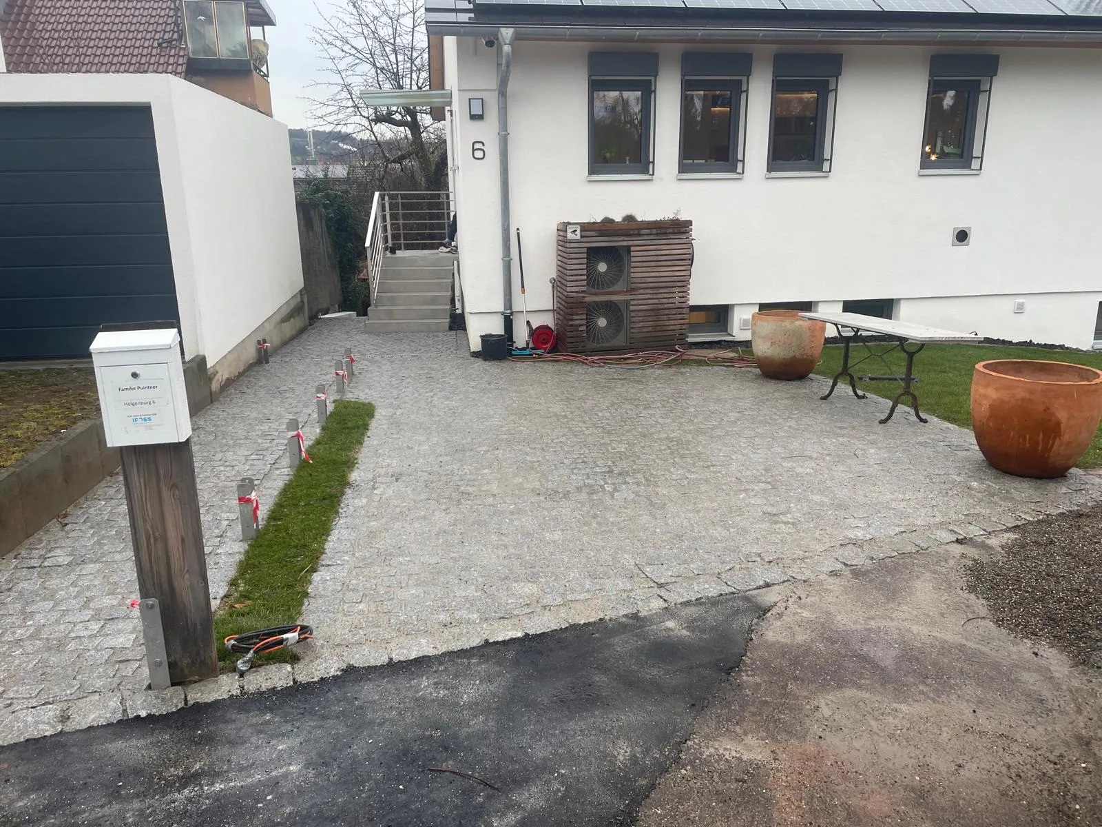 Gepflasterter Hof mit Briefkasten und Beetstreifen vor einem Wohnhaus